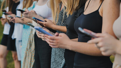 Students standing together, sharing and comparing online content on their smartphones