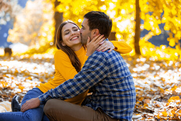 Fototapeta premium Husband kisses his wife on a picnic date in the park.