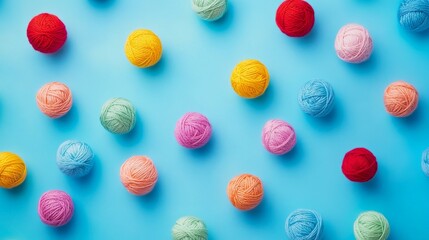 Fototapeta premium Brightly colored yarn balls scattered in an artistic, playful pattern on a vibrant blue background. This eye-catching display of colorful materials is ideal for craft, knitting, or crochet-related