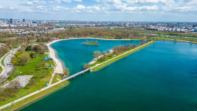 Aerial drone view of Park Jarun in Zagreb, showcasing stunning blue water, lush greenery, and the nearby Sava River Park features excellent bicycle roads, perfect for cycling and outdoor activities
