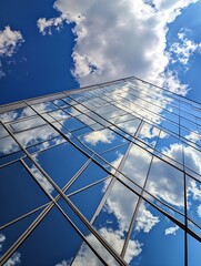 Obraz premium Modern High Rise Building Reflecting Blue Sky and Clouds in Urban Area : Generative AI