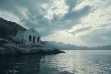 Chapel on Rocky Coastline under Cloudy Sky at Dawn, Tranquil Water Reflection and Distant Mountains