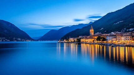 Stunning evening view of a serene lakeside town illuminated by golden lights against a mountain backdrop : Generative AI
