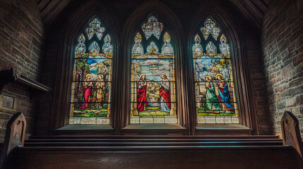 Obraz premium A beautifully crafted stained glass window depicting biblical scenes, showcasing vibrant colors and intricate designs in a gothic architectural setting.