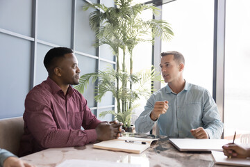Young businessman makes formal presentation to colleagues or business partners in modern office...