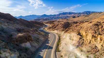 Fototapeta premium Aerial view of a winding road through rugged desert mountains under a clear blue sky : Generative AI