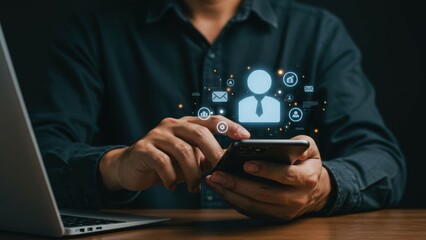 Man using smartphone at table with laptop, surrounded by digital network icons. Business professional connecting online, managing digital profile. Futuristic communication, optimization concept.