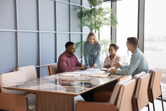 Group of professionals discussing strategy, working collaboratively on project gathered together in modern conference room. Multiethnic shareholders reviewing details of business proposal or contract