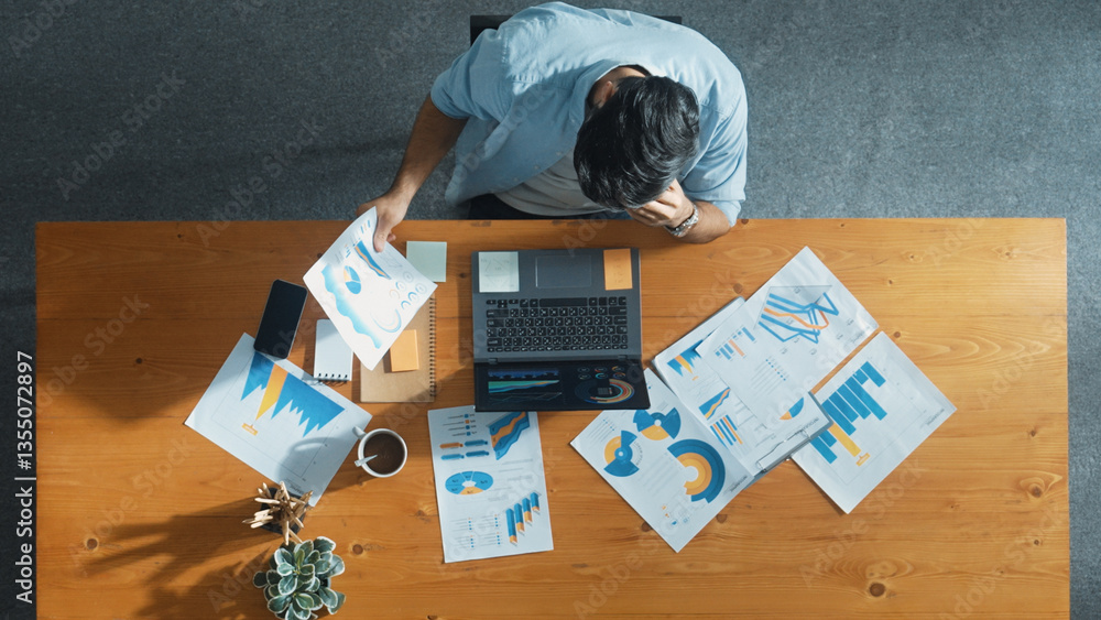 Poster top aerial view of stressful smart manager working on laptop while looking at data analysis. leader 