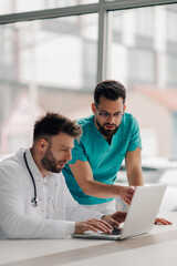 Doctors using laptop and discussing about patient diagnosis in hospital office