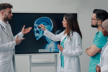 Doctors discussing head x ray on digital display in hospital meeting room