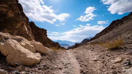 Obraz premium A breathtaking view of a rocky mountain path under a bright blue sky with clouds : Generative AI