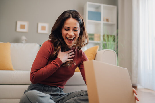 Excited woman opening a surprise package at home