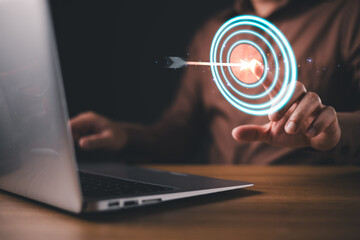 A person interacts with a futuristic digital target interface, symbolizing business goals,...