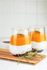 Two servings of sweet raw dessert with chia seeds, pumpkin or mango