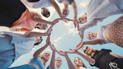 Obraz premium Group of school friends making a circle with their hands against a blue sky, symbolizing unity, teamwork and friendship