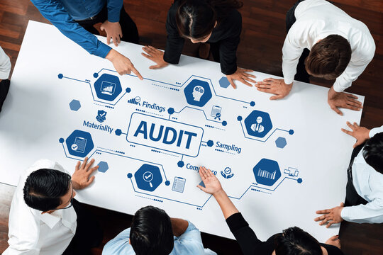 A diverse group of business professionals engaged in an interactive audit process, analyzing key findings and strategies presented on a large table. Amity
