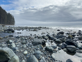 View of clouds over the Pacific Ocean from a rocky treelined beach on Vancouver Island