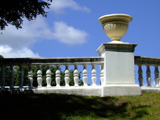 Elegant white railing with classical urn against a blue sky in a serene park setting