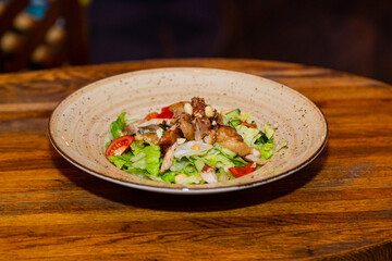 Salad with meat and nuts on a plate on a wooden table.Delicious food. overall plan