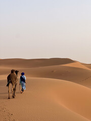 Berber man and his camel walk alone in Erga Chegaga desert, Morocco