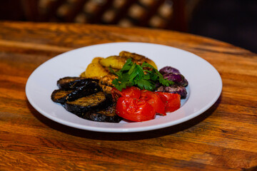 Grilled baked vegetables in a white plate on a wooden table. healthy eating