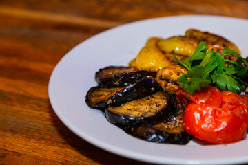 Grilled baked vegetables in a white plate on a wooden table. tasty healthy food. healthy eating. close-up on the left