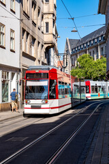 A vibrant from Erfurt, Thuringia, featuring a modern red and white tram navigating through the city's historic streets