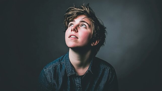 Young person looking up, thoughtful expression, denim shirt. - Powered by Adobe