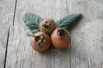 Three Ripe Medlar Fruits Placed on a Wooden Table in Natural Light