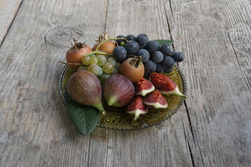 Assorted Fresh Fruits Including Grapes, Figs, and Medlar on a Wooden Plate
