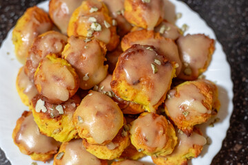 Bright orange pumpkin cookies baked in the oven, covered with icing, on a white plate