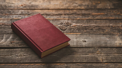 Red book with textured cover rests on rustic wooden surface, showcasing a simple yet elegant presentation, ideal for book cover mockup or literary themes