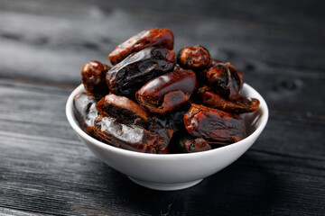 Dried sweet pitted dates in white bowl. Healthy food