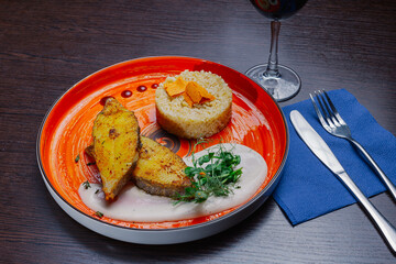 Grilled fresh red fish lies on a plate along with a side dish and sauce. delicious fresh wholesome food in the restaurant. cutlery on a napkin. red wine in a glass. medium shot