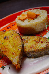 Grilled fresh red fish lies on a plate along with a side dish and sauce. delicious fresh Healthy food in the restaurant.fish with herbs and garnish