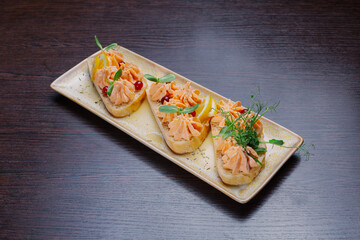 White bread sandwiches with fish cream and herbs on a white plate