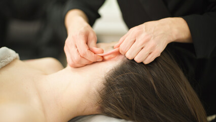 hands of a masseur doing facial massage. cosmetic procedures. ear massage  relaxation. Closeup.  Soft focus