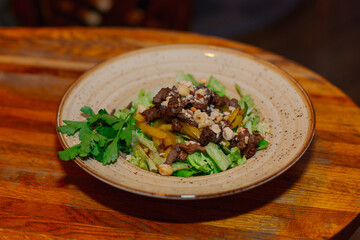 Delicious fresh salad with vegetables meat and peanuts on a beautiful plate on the table in the restaurant