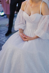 Beautiful tender hands of a bride who sits in a wedding dress on her wedding day