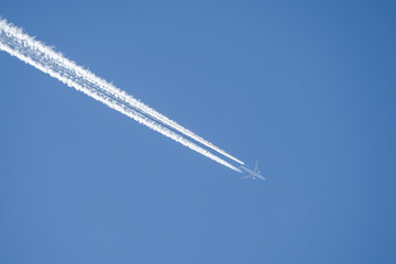 a twin engined jet liner aircraft in deep blue sky, contrails vapour trails
