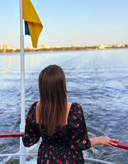 the girl on the ship stands with her back and looks at the water