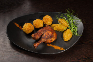 Very healthy roast duck thigh with potatoes and greens on a black plate on a wooden table serving in a restaurant. nice decoration of the dish. diet food in a restaurant. new recipe