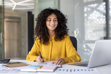 Successful businesswoman financier doing paperwork inside office. Woman with documents and papers, satisfied with financial results smiling. Accountant preparing report and filling in data.