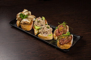 Three types of bruschetta on the table on a black plate beautiful serving in a restaurant. classic snack. snack for alcohol