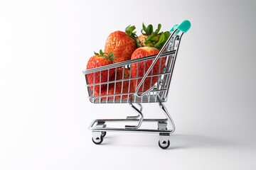 Shopping cart filled with fresh strawberries on white background