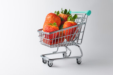 Shopping cart filled with fresh strawberries on white background