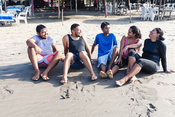 group of young latin friends sitting on the beach in pacific ocean in Acapulco Mexico Latin...