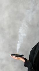 Tranquil moment with incense smoke and a minimalist hand holding black tray