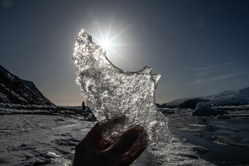 a piece of ice from Jökulsárlón, the glacier lagoon in iceland, with the sun in the background